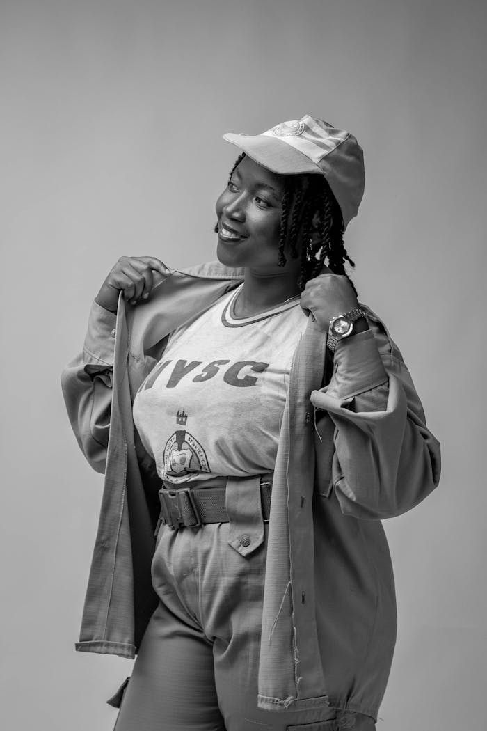 A smiling woman poses confidently in uniform against a gray backdrop.
