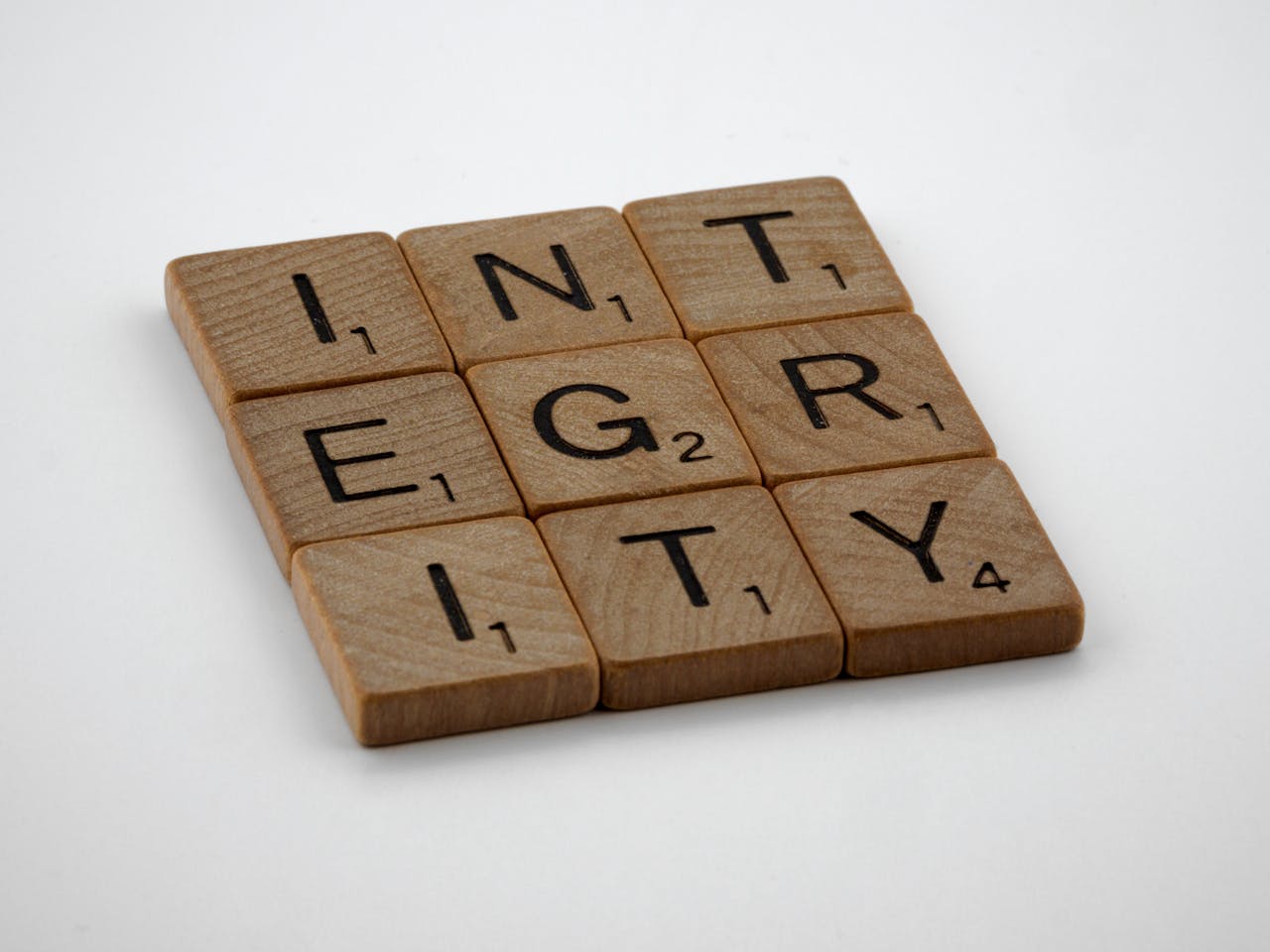 Wooden scrabble tiles spelling INTEGRITY on a white background, emphasizing honesty and ethics.