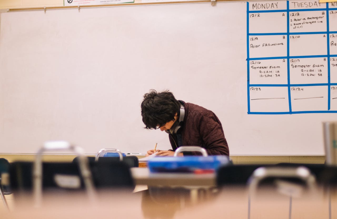 A high school student studying and solving problems in a classroom setting.